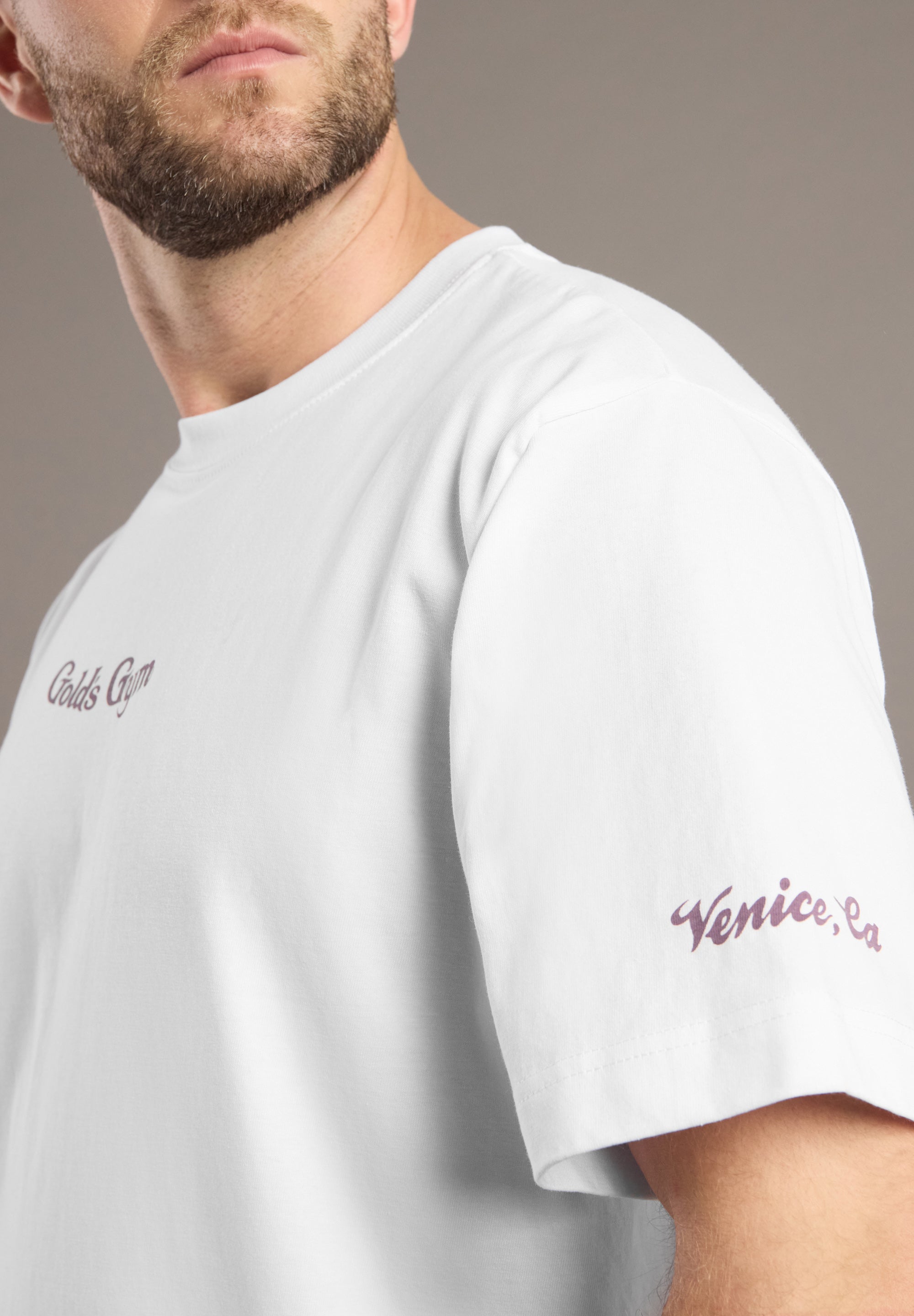 White t-shirt with embroidered text worn by a person, on a neutral background