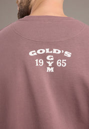 Back of a maroon sweatshirt with 'Gold's Gym 1965' text on a neutral background