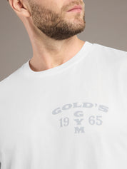 White t-shirt with 'Gold's Gym' logo worn by a person, on a neutral background
