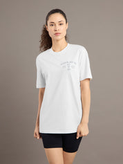 Woman wearing a white t-shirt with text on a brown background