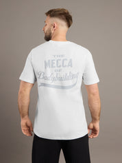 Man wearing a white t-shirt with text on the back, standing against a plain background