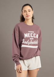 Person wearing a mauve sweatshirt with text on it against a plain background