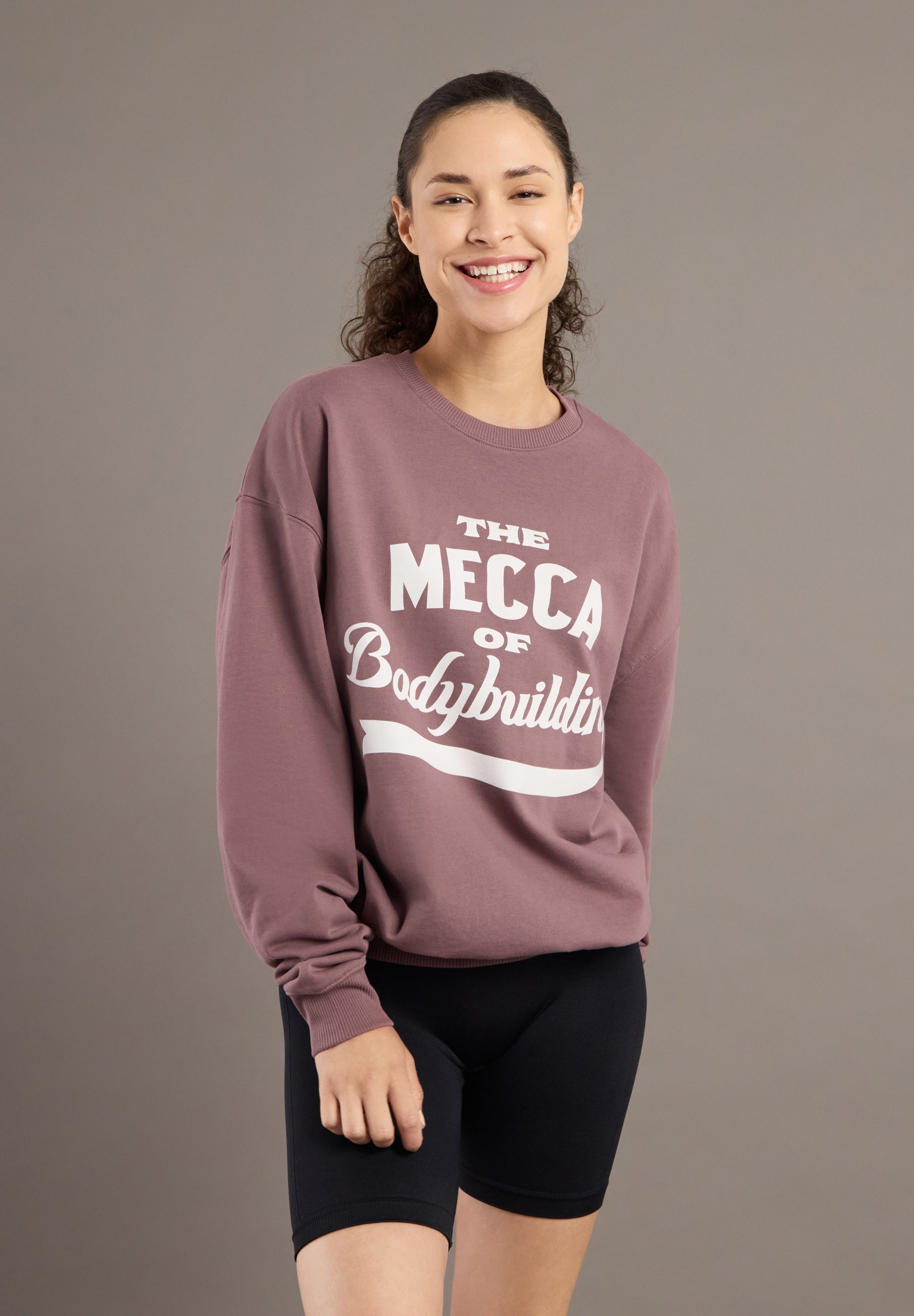 Woman wearing a mauve sweatshirt with text on a brown background