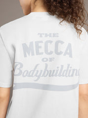 Person wearing a white t-shirt with 'The Mecca of Bodybuilding' text on the back.