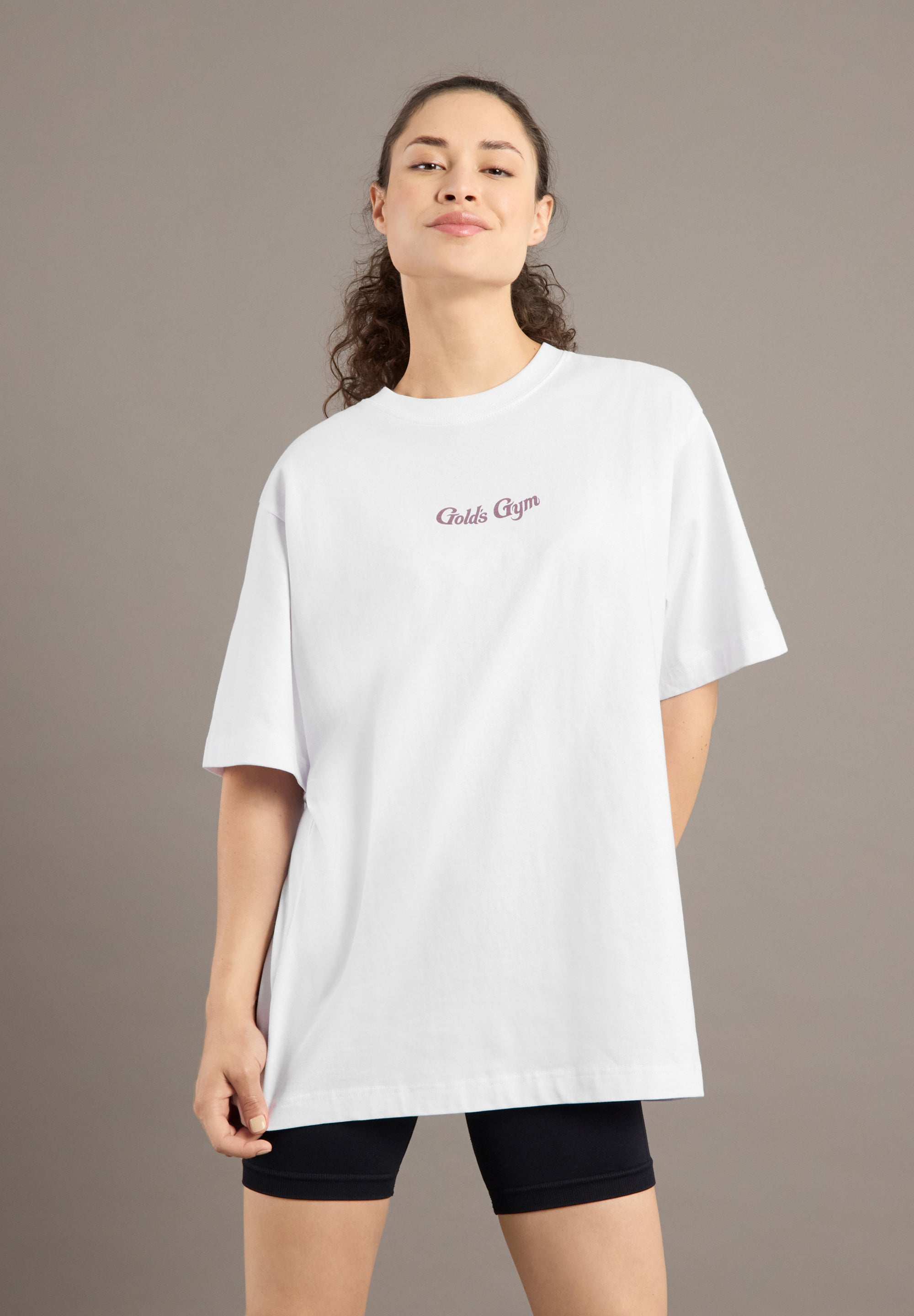 Woman wearing a white oversized t-shirt with text on a plain background