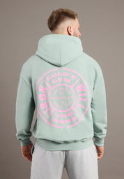 Person wearing a light green hoodie with pink text on the back against a gray background
