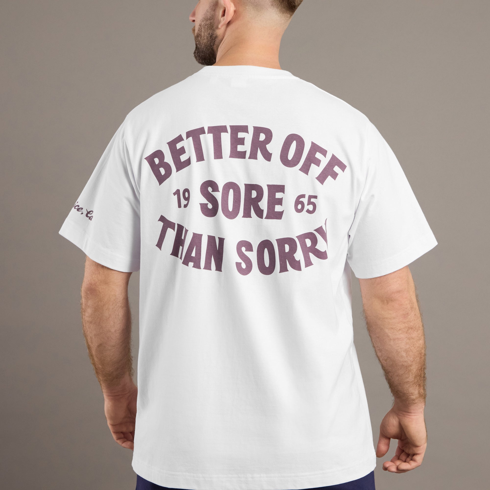Man wearing a white t-shirt with text on the back against a gray background