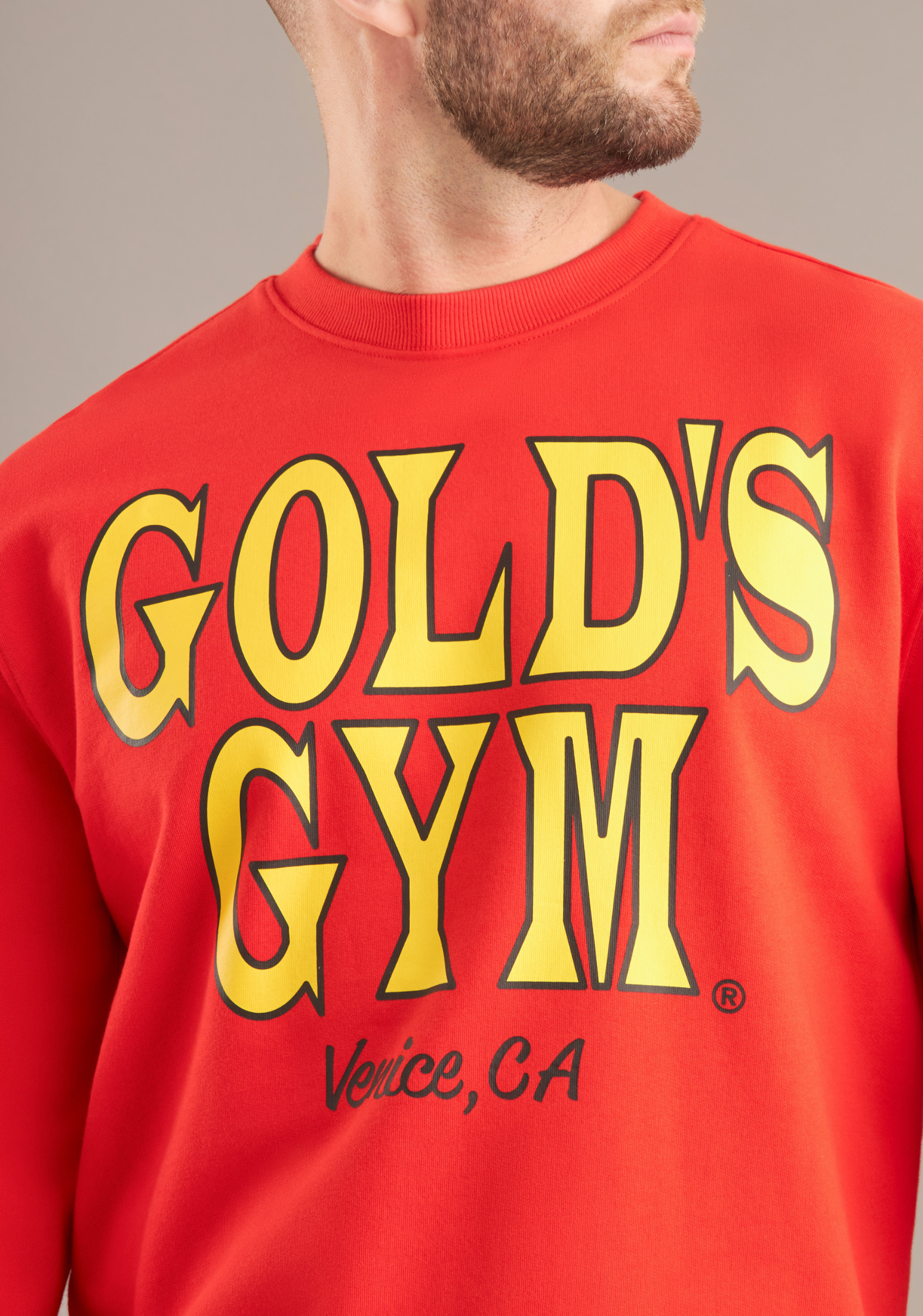 Red Gold's Gym sweatshirt with yellow text on a neutral background