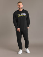Man wearing a black sweatshirt with 'The Megga' logo on a brown background