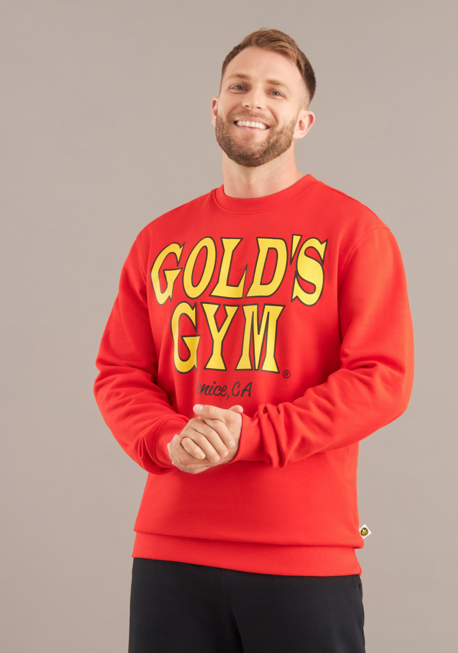 Man wearing a red 'Gold's Gym' sweatshirt against a gray background