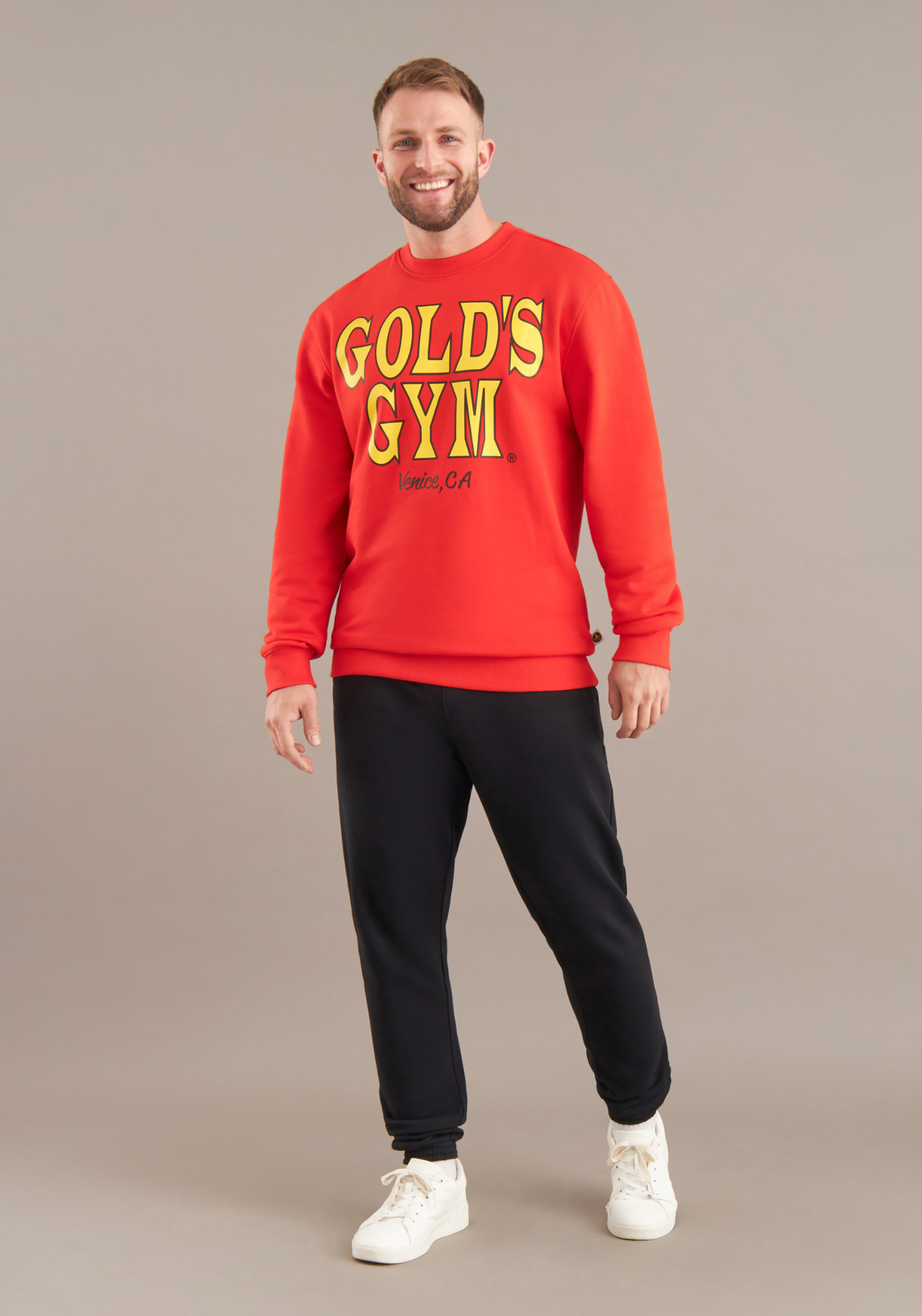 Person wearing a red Gold's Gym sweatshirt on a beige background