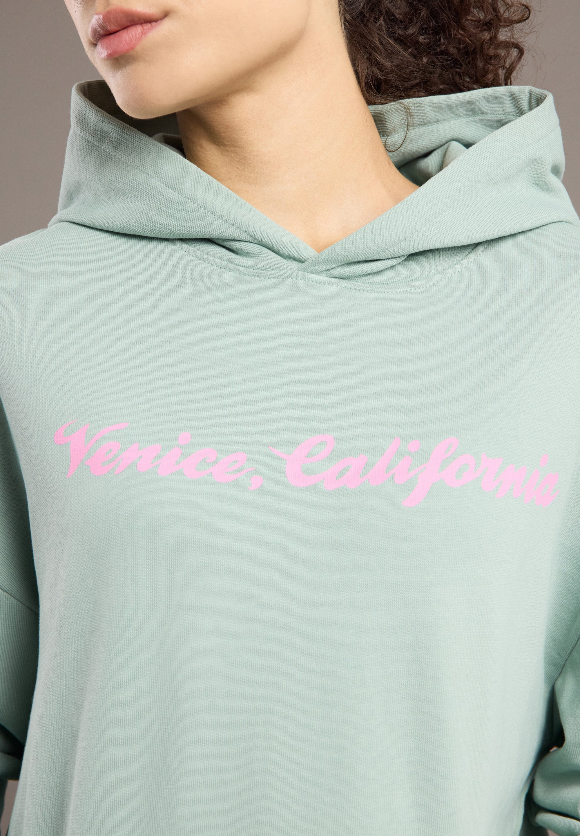 Light green hoodie with 'Venice, California' text in pink on a neutral background