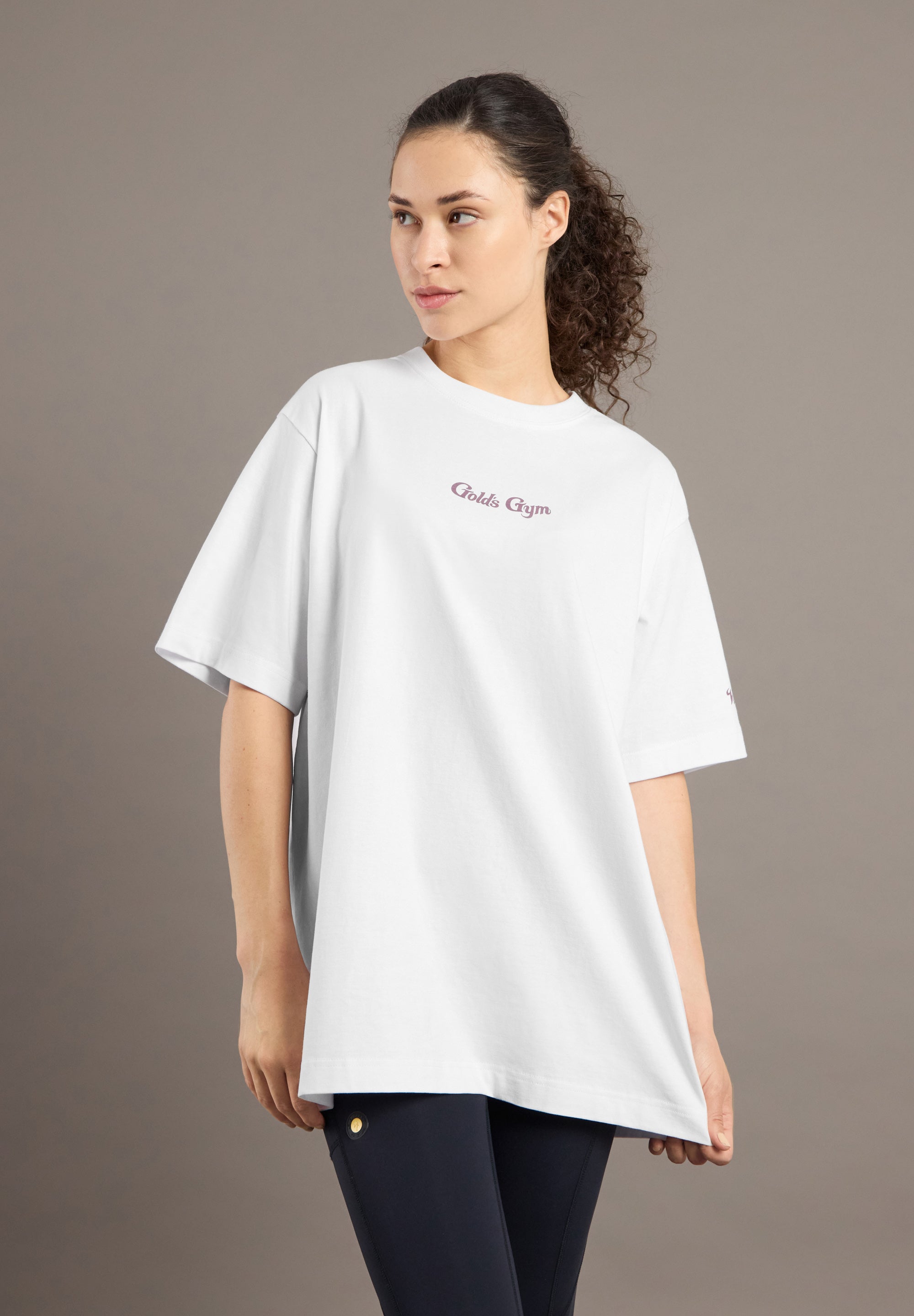 Woman wearing a white oversized t-shirt with text on a plain background
